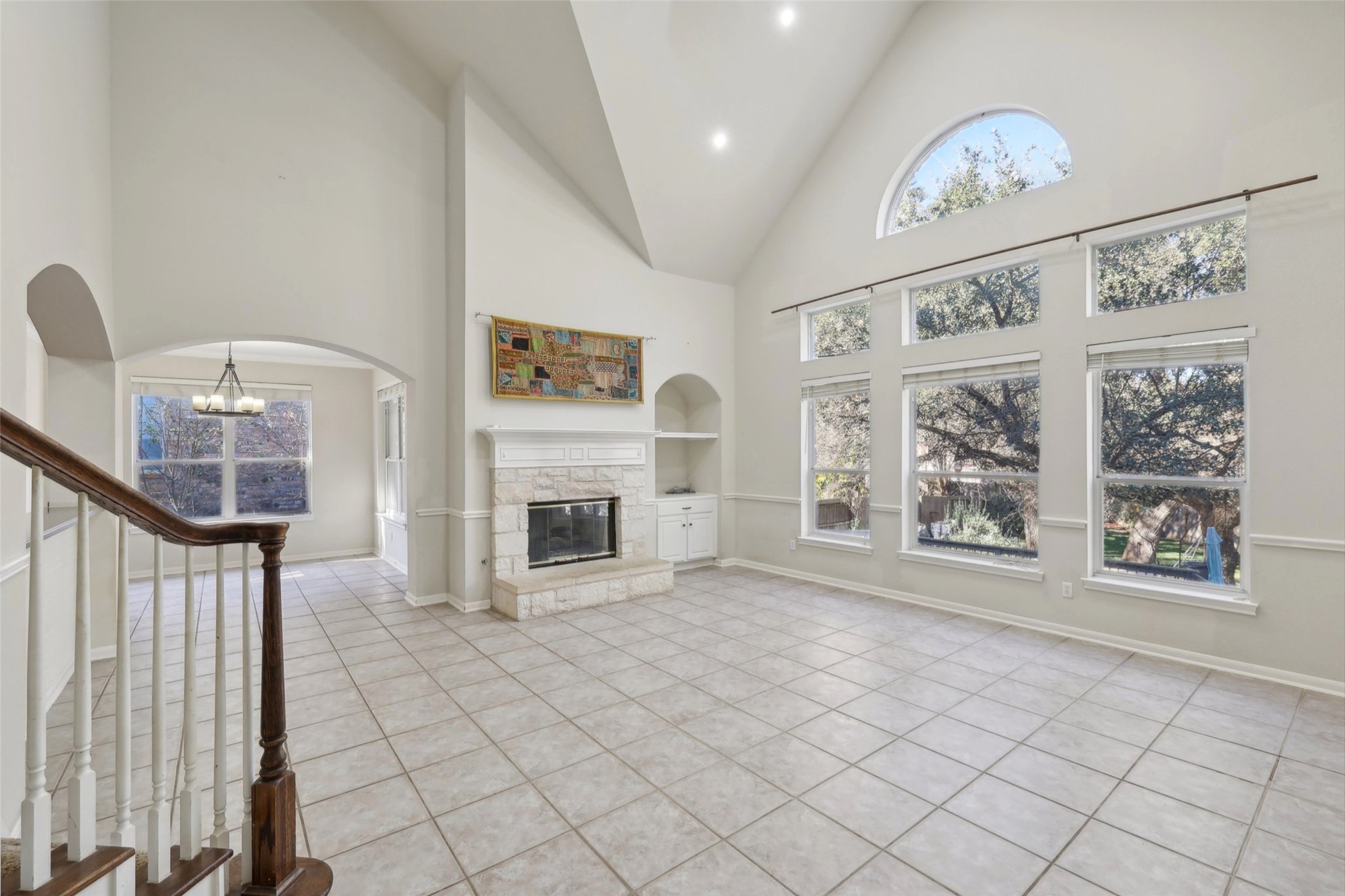 2948 Grimes Ranch Road Austin, TX 78732 - Photo 7 of 40 Unfurnished living room with healthy amount of natural light, a stone fireplace, built in shelves, tile patterned floors, and recessed lighting