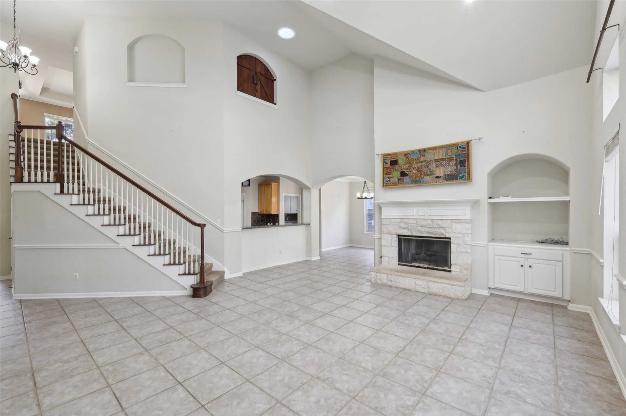 2948 Grimes Ranch Road Austin, TX 78732 - Photo 8 of 40 Unfurnished living room with a fireplace, built in features, high vaulted ceiling, light tile patterned flooring, and stairway