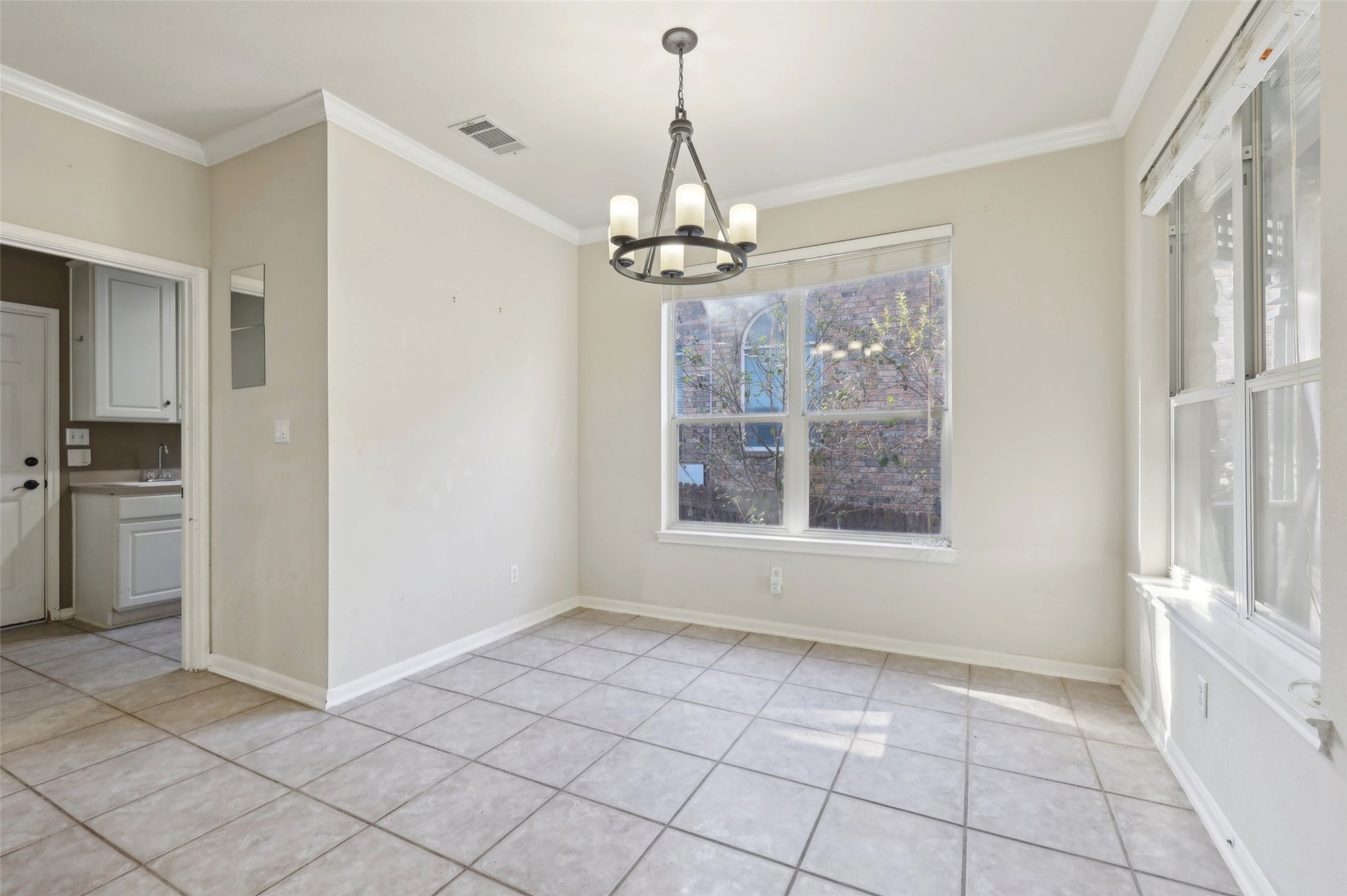 2948 Grimes Ranch Road Austin, TX 78732 - Photo 10 of 40 Unfurnished dining area with a chandelier, ornamental molding, light tile patterned floors, baseboards, and a sink
