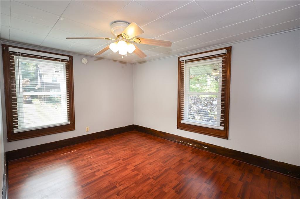 311 Center Street Slippery Rock, PA 16057 - Photo 20 of 32 an empty room with wooden floor chandelier fan and windows