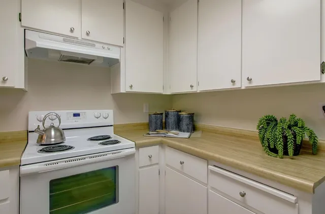 a kitchen with a stove and white cabinets