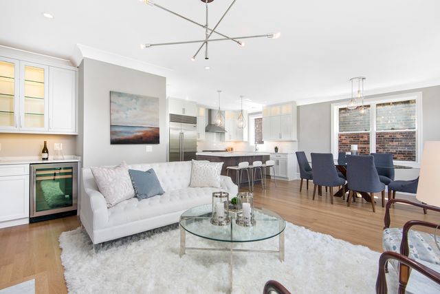 a living room with furniture kitchen view and a wooden floor