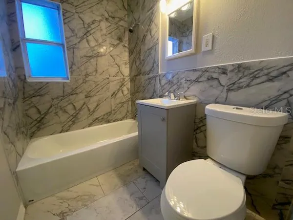 a white toilet sitting next to a bathroom sink and tub