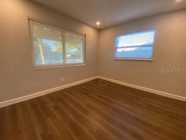 a view of an empty room with wooden floor and a window