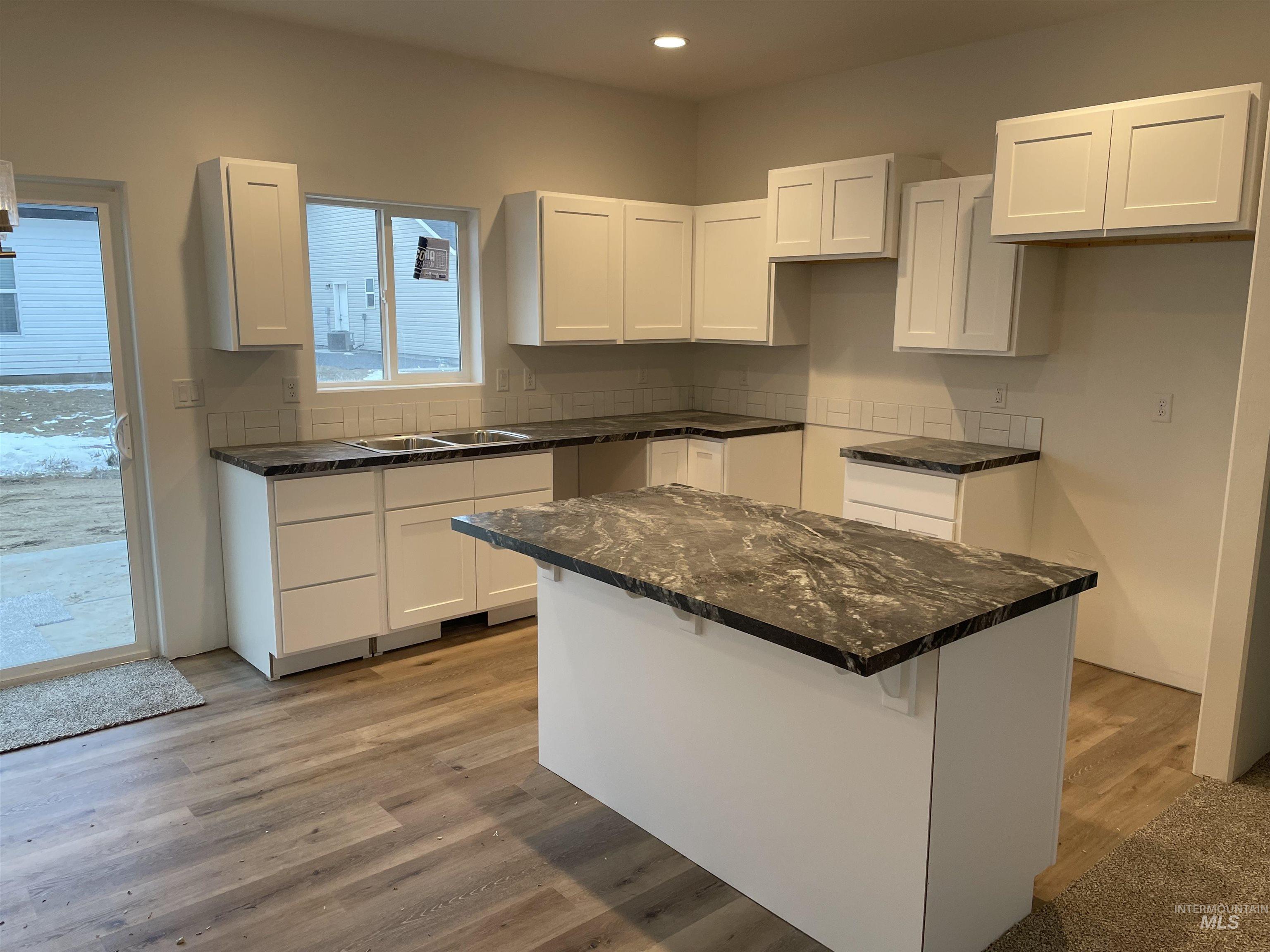 937 Roen Road Jerome, ID 83338 - Photo 2 of 4 Kitchen with white cabinetry, a kitchen island, a kitchen bar, light wood finished floors, and recessed lighting