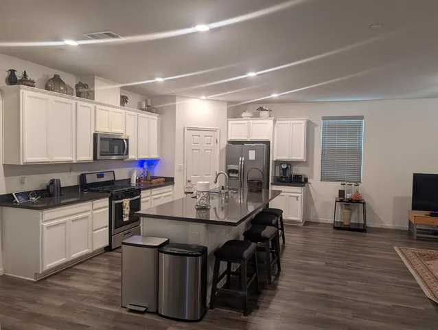 a kitchen with kitchen island granite countertop a sink cabinets and wooden floor
