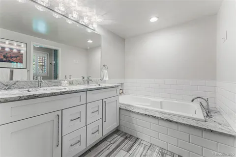 a bathroom with a granite countertop bathtub sink double and mirror
