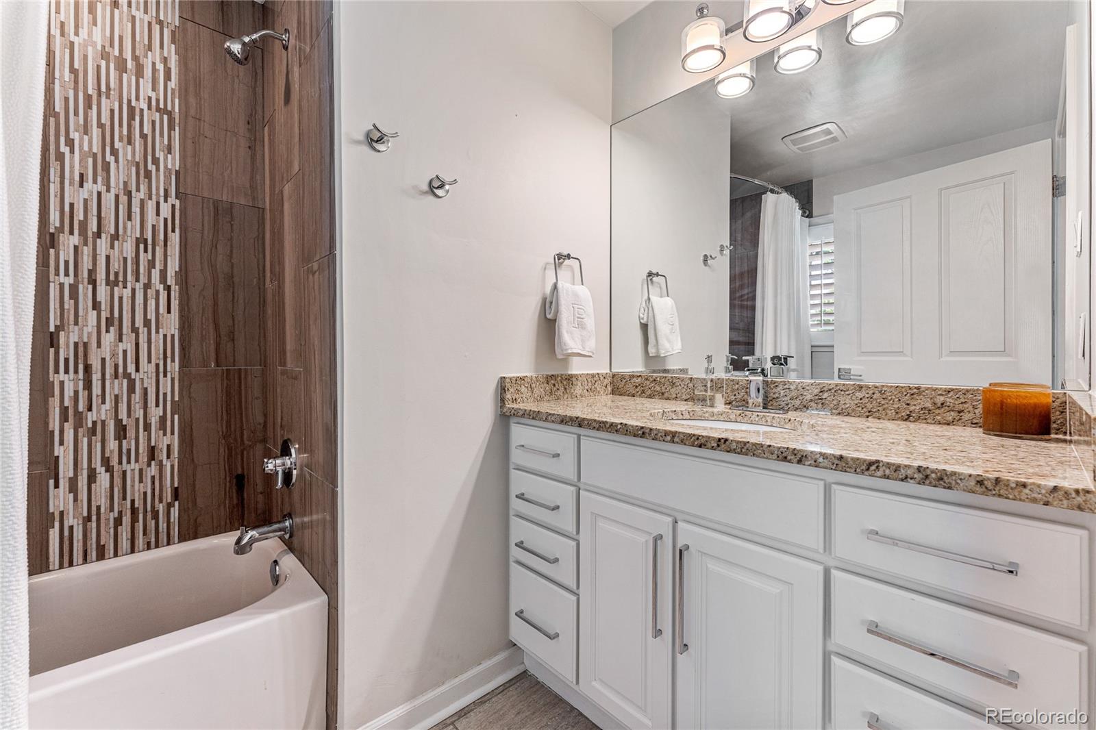 3800 East Dartmouth Avenue Denver, CO 80210 - Photo 26 of 50 a bathroom with a granite countertop sink a mirror and a bathtub