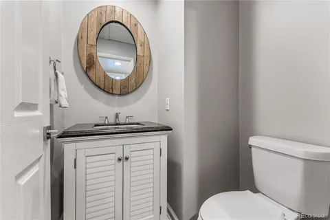 a bathroom with a granite countertop toilet a sink and a mirror