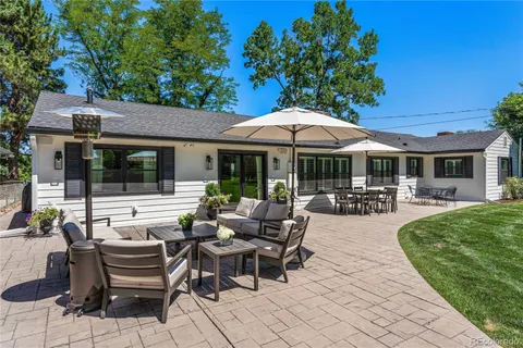 a view of a patio with dining table and chairs under an umbrella with a barbeque grill and couches
