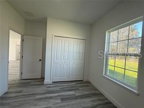 5981 Southwest 154th Place Ocala, FL 34473 - Photo 11 of 18 an empty room with wooden floor and windows