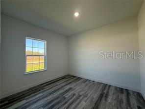 5981 Southwest 154th Place Ocala, FL 34473 - Photo 9 of 18 an empty room with wooden floor and windows