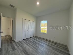 5981 Southwest 154th Place Ocala, FL 34473 - Photo 10 of 18 a view of an empty room with wooden floor and a window