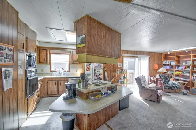 a living room with stainless steel appliances granite countertop furniture a couch and a large window