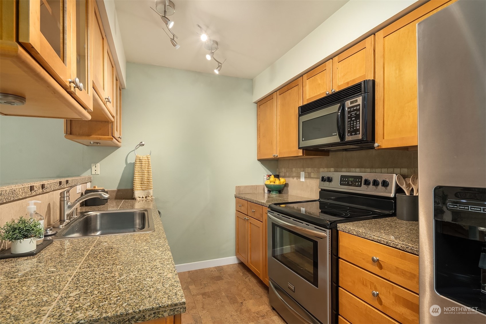 18930 Bothell Everett Highway, Unit D302 Bothell, WA 98012 - Photo 11 of 25 a kitchen with stainless steel appliances granite countertop a sink stove and microwave
