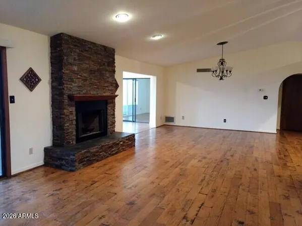 an empty room with wooden floor a fireplace and windows