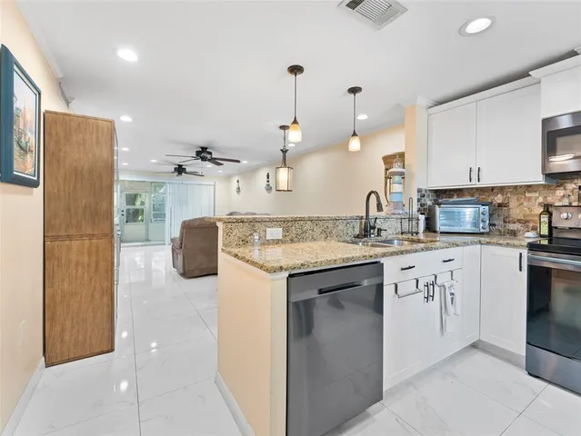 a kitchen with stainless steel appliances granite countertop a sink a stove and a refrigerator