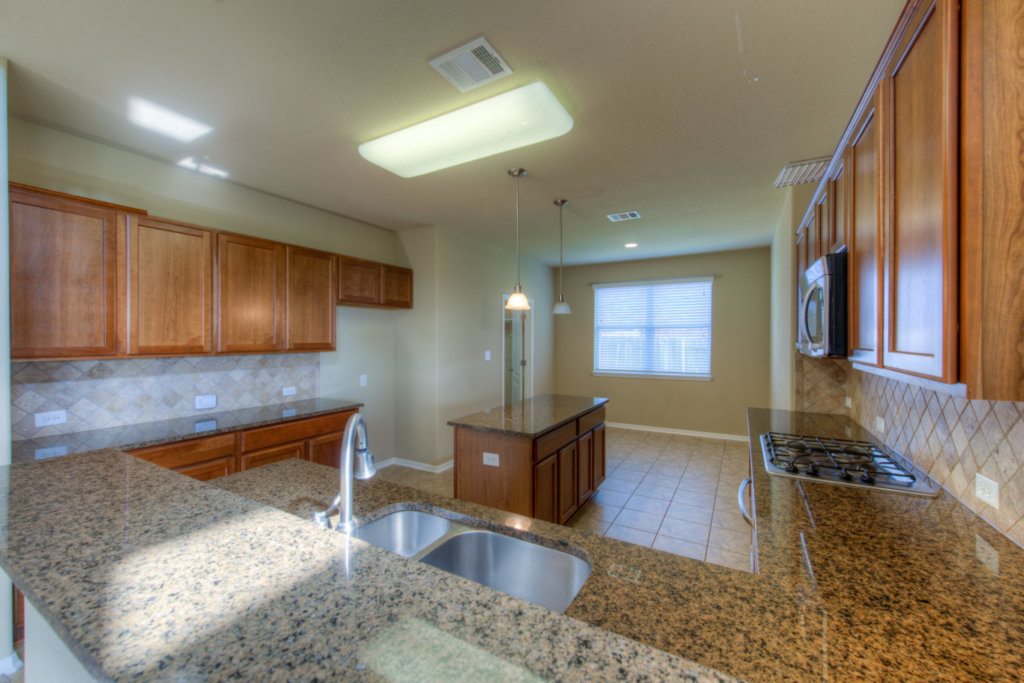 403 Limestone Trail Austin, TX 78737 - Photo 10 of 18 A well-lit kitchen with granite countertops and a functional island, perfect for culinary endeavors.