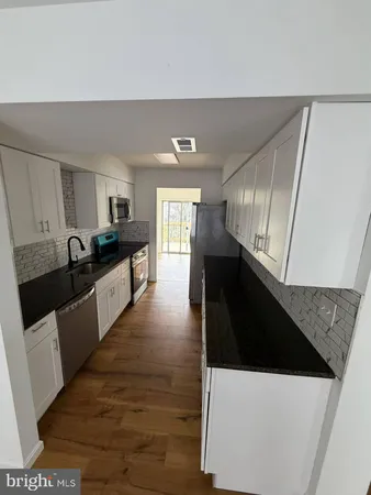 a kitchen with granite countertop a refrigerator a sink dishwasher stove and white cabinets