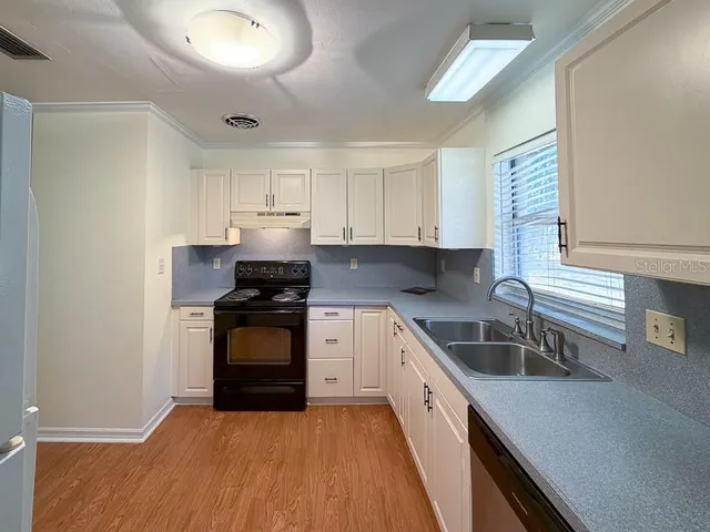a kitchen with granite countertop a stove sink and cabinets
