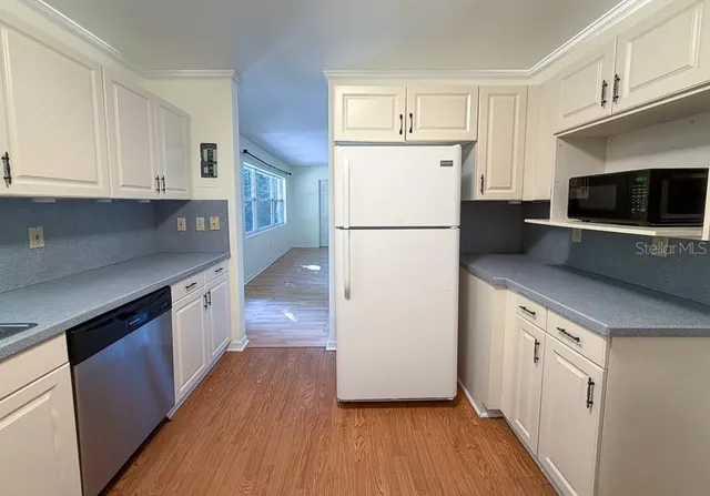 a kitchen with a refrigerator a stove top oven a sink and cabinets with wooden floor