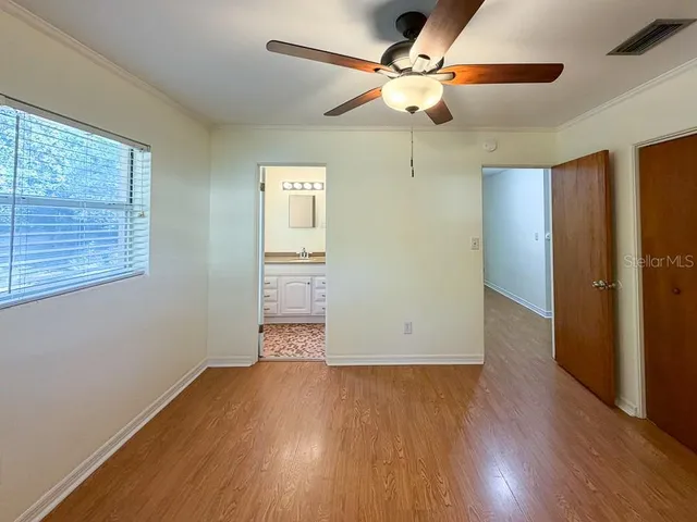 an empty room with wooden floor chandelier fan and windows