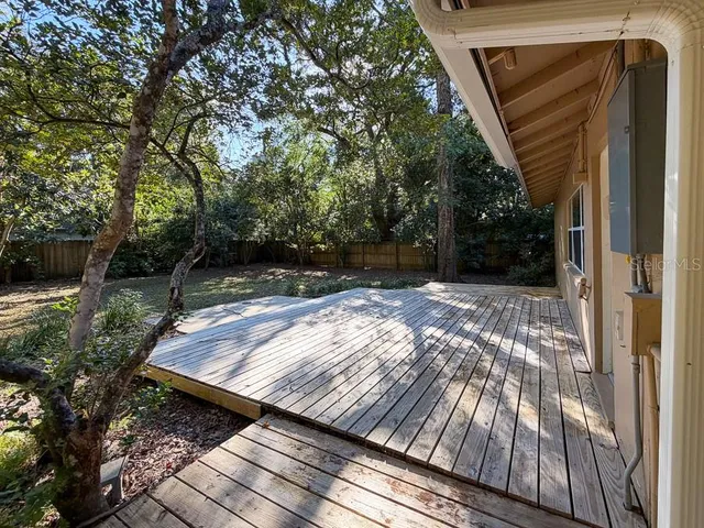 a view of backyard with wooden floor and fence