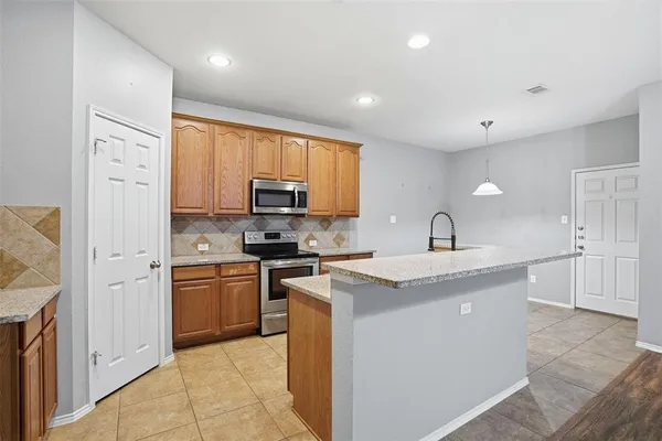 a kitchen with stainless steel appliances granite countertop a stove top oven a sink a refrigerator and white cabinets