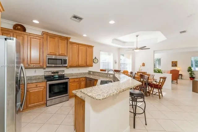 a open kitchen with stainless steel appliances granite countertop a stove top oven a sink dishwasher a dining table and chairs with wooden floor