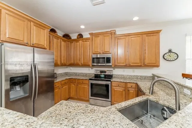 a kitchen with stainless steel appliances granite countertop a sink a stove and refrigerator