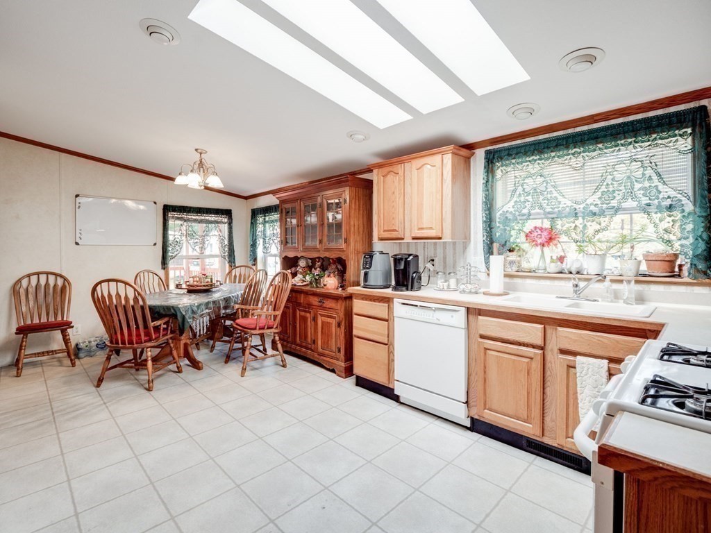 17 Medallion Road Holbrook, MA 02343 - Photo 14 of 39 a large white open kitchen with stainless steel appliances granite countertop a stove top oven a sink a dining table and chairs with the large mirror