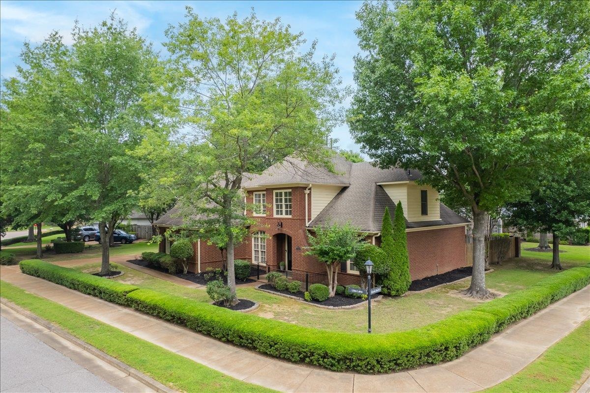 1876 Liles Lane Collierville, TN 38017 - Photo 2 of 36 Traditional brick residence featuring a prominent corner lot, mature trees, manicured hedges, and a gabled roofline
