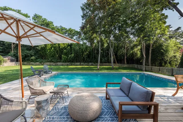 a view of a swimming pool and lounge chairs in back yard of the house
