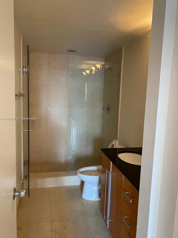 a bathroom with a granite countertop shower and a toilet