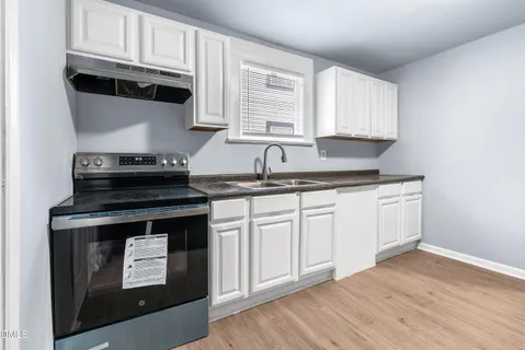 a kitchen with granite countertop white cabinets and sink