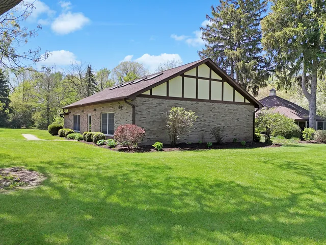 a view of a house with a big yard and large trees