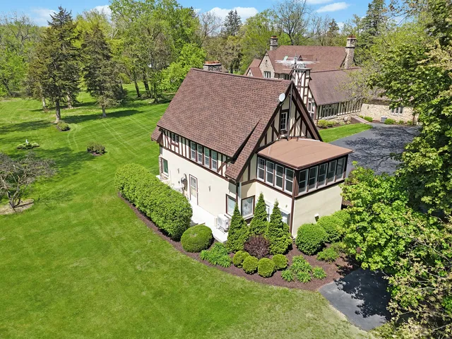 an aerial view of residential house with outdoor space and trees all around