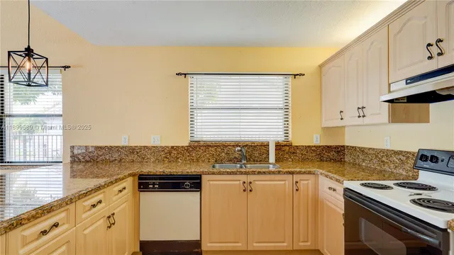 a kitchen with granite countertop a sink stove and cabinets