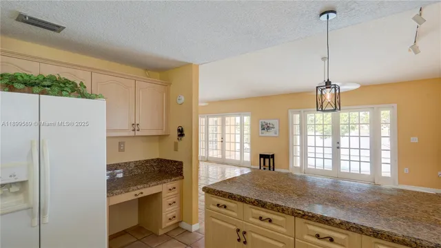 a kitchen with stainless steel appliances granite countertop a refrigerator a sink dishwasher and white cabinets with wooden floor