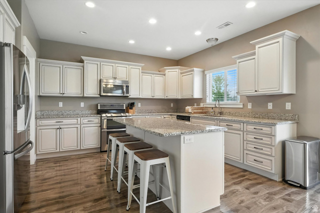 1055 West 2500th Street South Logan, UT 84321 - Photo 11 of 53 Spacious kitchen, large island with seating, extensive white cabinetry, granite countertops, stainless steel appliances, and wood-finish flooring