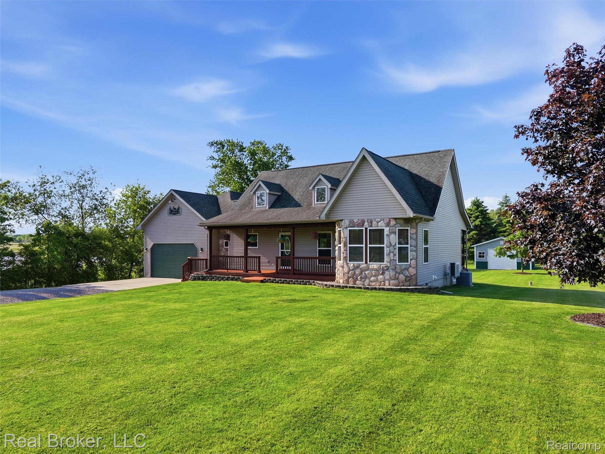 7271 West Ray Road Gaines, MI 48436 - Photo 8 of 48 Gabled home with stone and siding exterior, featuring a front porch with railing and an attached garage with green door