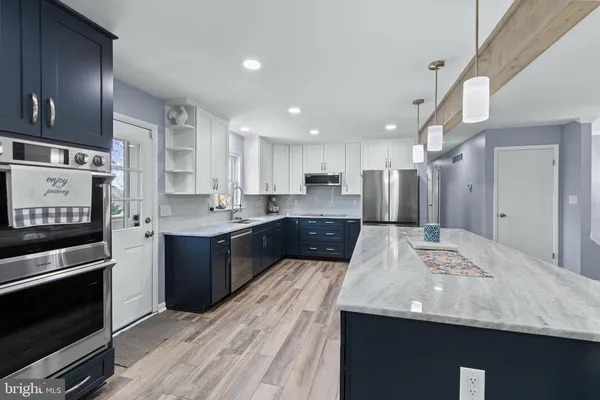 a kitchen with stainless steel appliances granite countertop a sink and cabinets with wooden floor