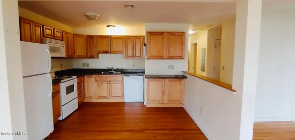 a kitchen with granite countertop a refrigerator a sink and wooden floors