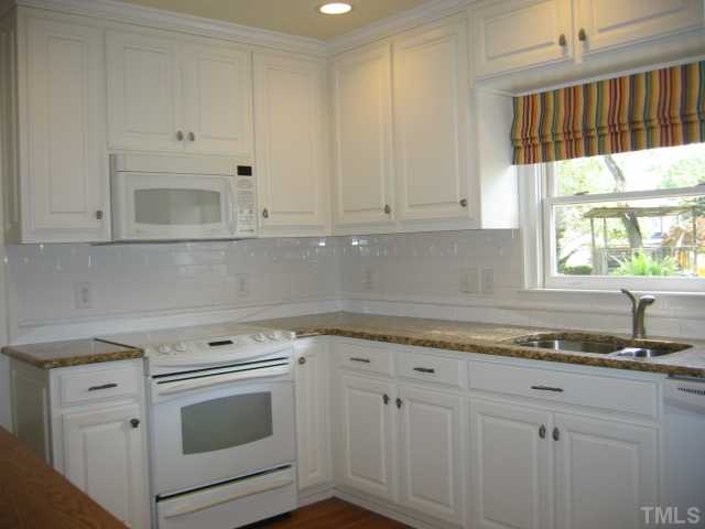 1306 Rand Drive Raleigh, NC 27608 - Photo 6 of 12 a kitchen with granite countertop white cabinets and white appliances