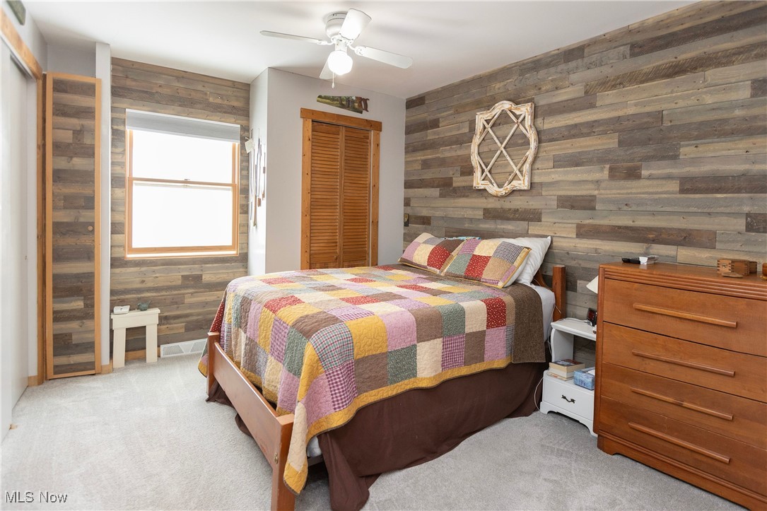 253 Sunset Road Avon Lake, OH 44012 - Photo 17 of 33 Bedroom with a ceiling fan, light carpet, and wood walls