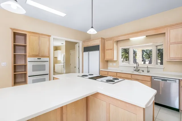 a kitchen with granite countertop a stove a sink a refrigerator and a stove