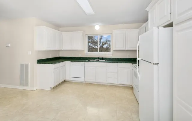 an empty room with a chandelier fan and windows