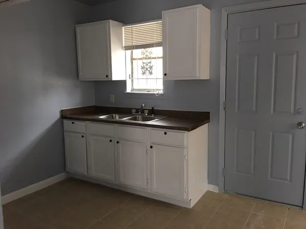 a kitchen with granite countertop white cabinets and a sink