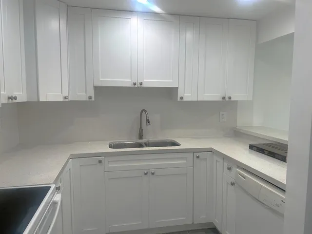 a kitchen with white cabinets and sink