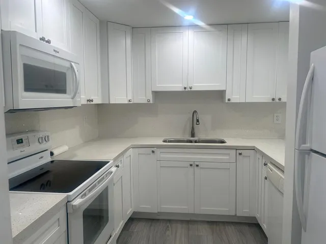 a kitchen with cabinets appliances a sink and a microwave